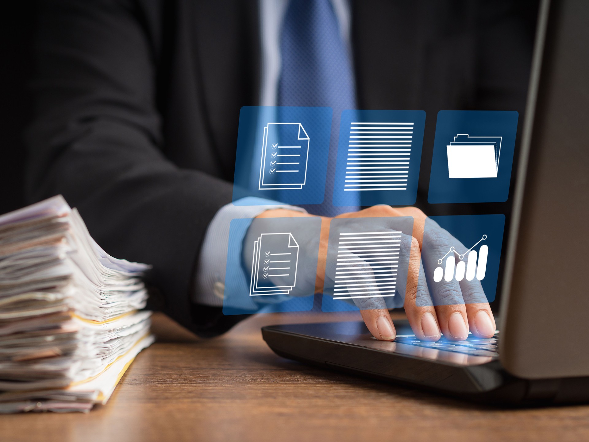 Businessman in a suit working at a laptop and digital documents with checkbox lists on virtual screen
